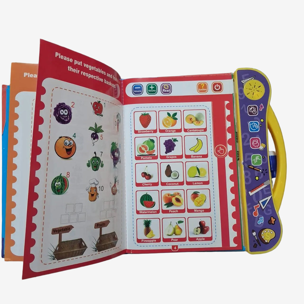 An open children's educational toy book with a yellow handle, showing fruit and vegetable matching pages on a glass tabletop. The book has red borders, colorful fruit illustrations, and a purple control panel on the handle with toy-like icons.
