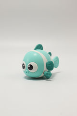 A small cartoon fish toy in mint green and white, resting on a reflective glass surface with a blurred store background.